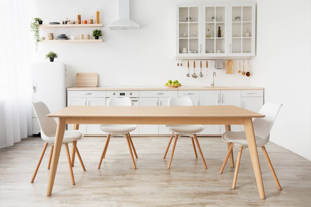 Lesena kuhinjska miza, obdana s štirimi kuhinjskimi stoli, je del stilsko dovršenega skandinavskega koncepta kuhinje.