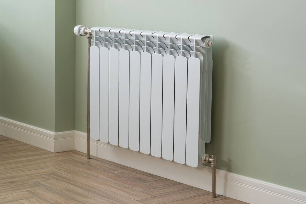 Centralno ogrevanje - pogled na lepo oblikovan radiator in pastelno zeleno steno.