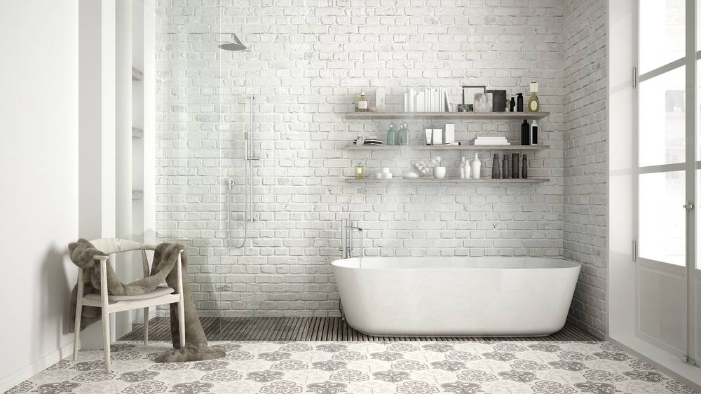 Pogled na moderno kopalnico in steno, ki jo krasijo male kopalniške ploščice, ki spominjajo na opeko.