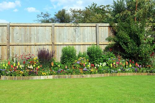 Visoka lesena vrtna ograja nudi veliko zasebnosti in lepo poudari
            cvetlični vrt.