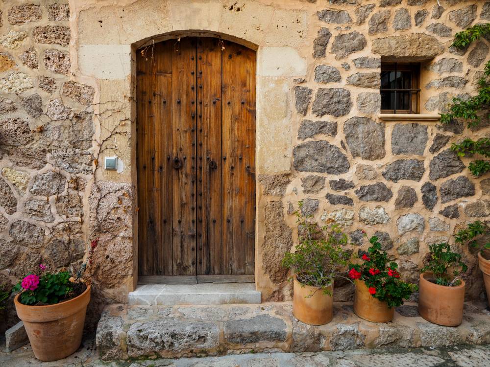 Lesena vrata stare kamnite hiše, obdane z lončnicami cvetlic, so prav romantičen prizor.