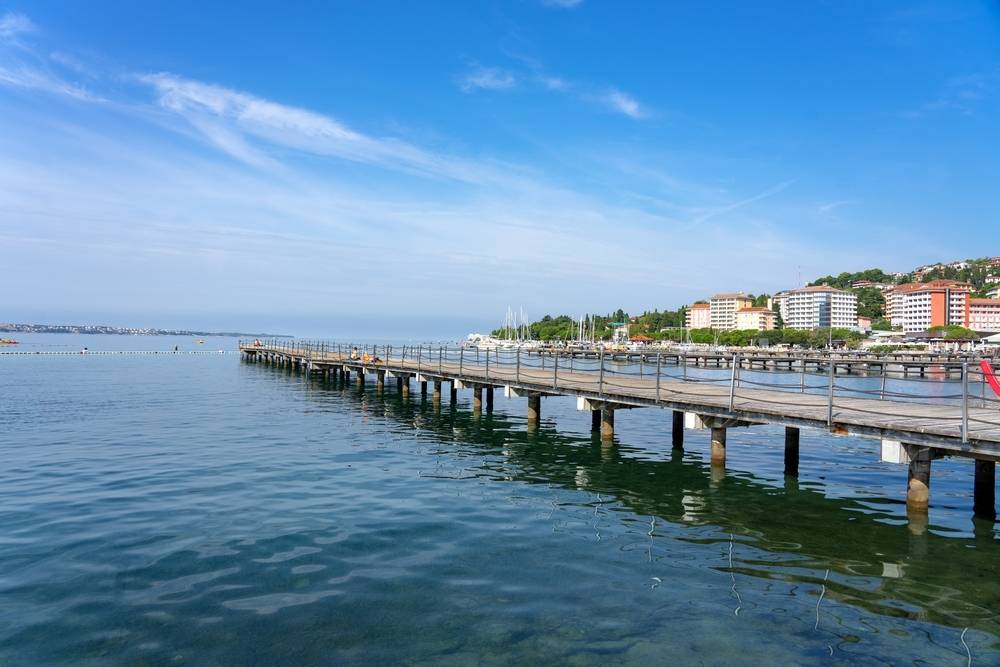 Portoroški pomol je v poletnih mesecih poln plavalcev, povsem zasedeni pa so tudi hotelski kompleksi v ozadju.