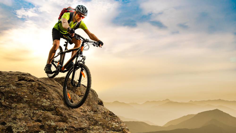 Pogled na gorsko kolo in kolesarja, ki pogumno premaguje skalnat gorski greben.