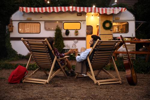 Par sedi pred prikolico in uživa v romantičnem večeru ob pivu.