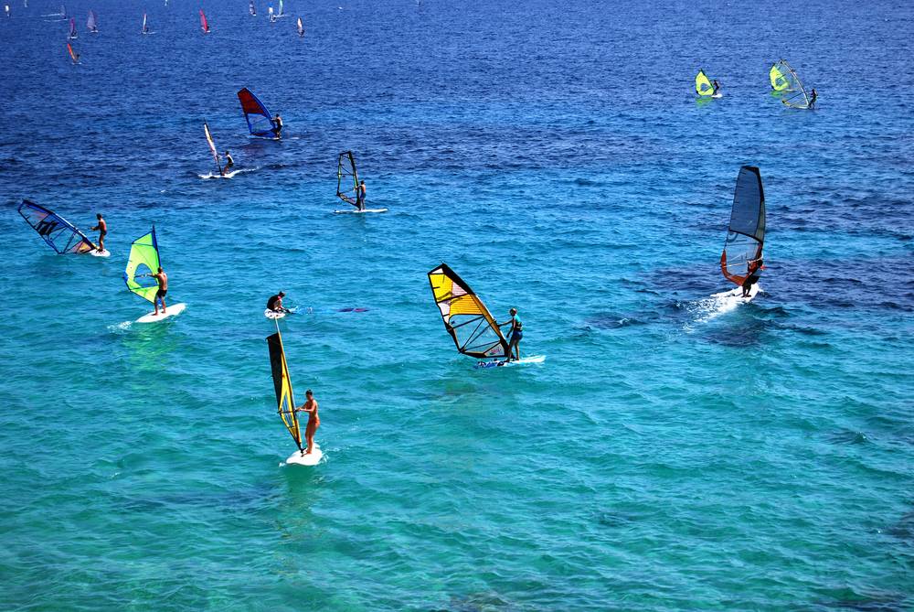 Pogled na deskarje, ki uživajo v kristalno zelenem morju na otoku Brač v Dalmaciji.