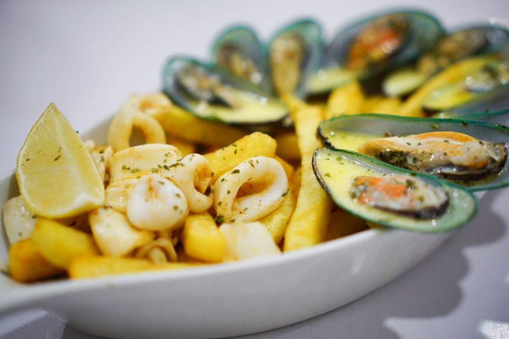 Sredozemski krožnik - kremaste zelene školjke, lignji in ocvrt krompirček z limono.