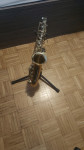 Alto Saxofon s stojalom in kovčkom ter opremo za igranje. (Thomann)
