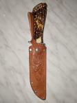 Nož z lovskim motivom v usnjenem etuiju