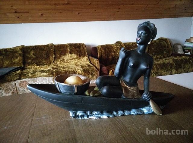 Kovinski kipec temnopolte ženske v čolnu